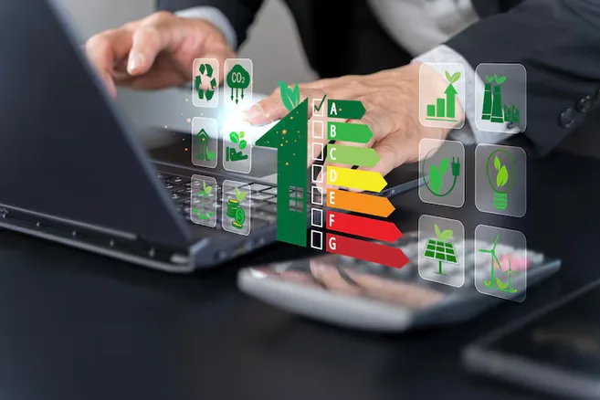 Mãos de empresário no notebook com classificação energética de A a G e ícones de sustentabilidade