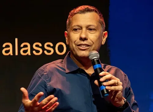 Rafael Galasso ao microfone num palco escuro