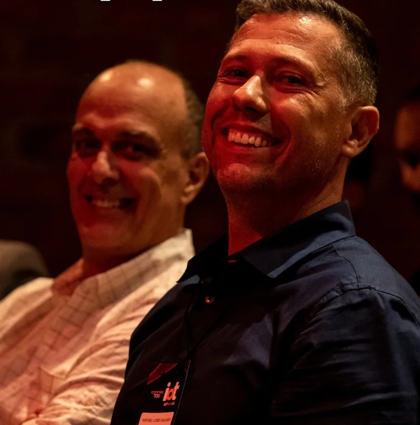 Participantes sorrindo em um evento da TEG, com crachá de credenciamento