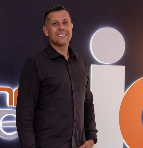 Rafael Galasso em contraluz no palco, diante do logo da TEG